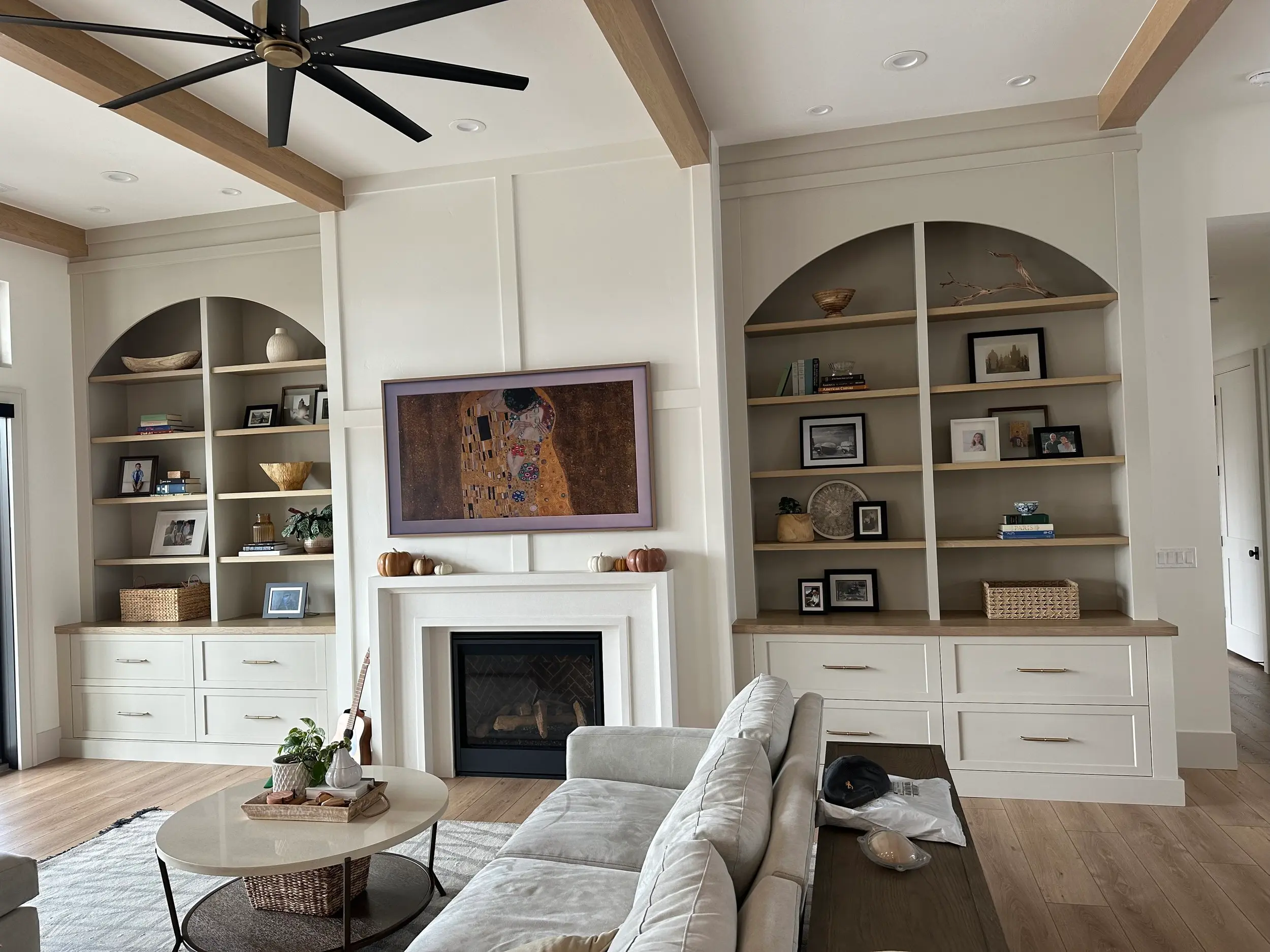Custom arched built-in cabinetry flanking a fireplace, featuring open display shelving, drawer storage, and hand-finished millwork detail.